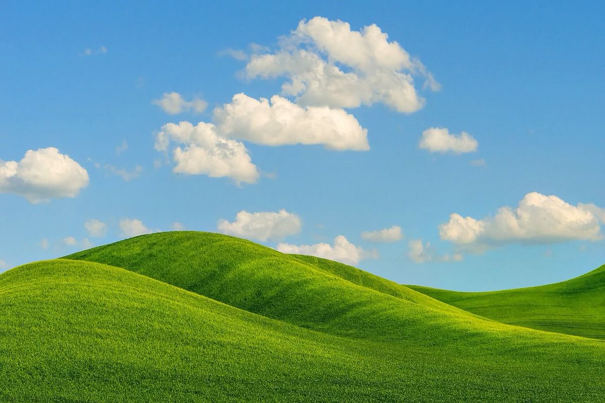 A grassy hills with a blue sky and clouds